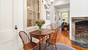 Un coin repas avec une table et des chaises en bois, un vase de fleurs et une cheminée.
