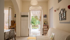 Ein gemütliches Wohnzimmer mit einer Couch, ein Essbereich mit Tisch und Stühlen sowie eine Küchenzeile mit Kühlschrank und Schränken.