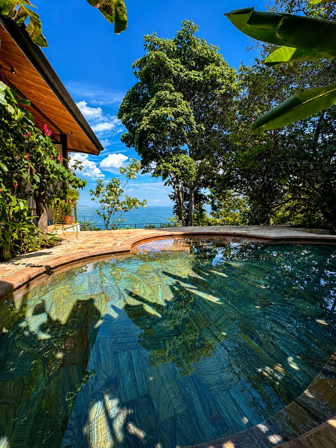 Vista despejada de una piscina con cubierta de madera y vista al mar.