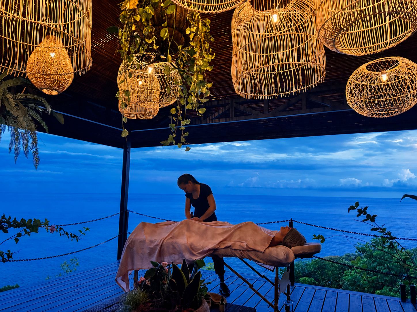 A massage therapy session taking place on a wooden deck with a view of the ocean.