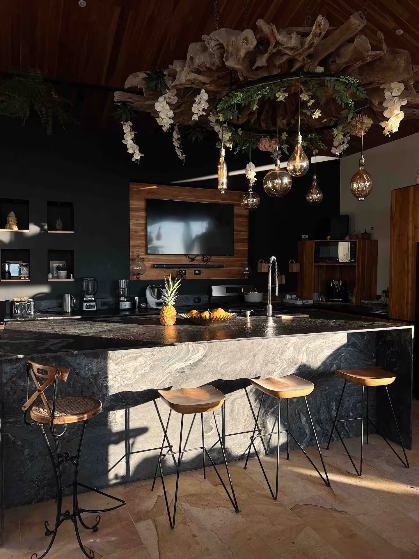 A modern kitchen with a large island, bar stools, and a TV mounted on the wall.