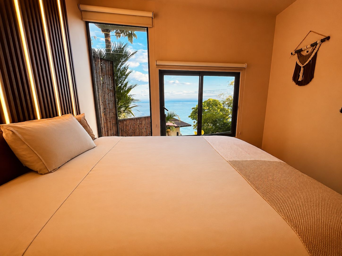 Un dormitorio con una cama grande, vista al mar y un balcón con barandilla.