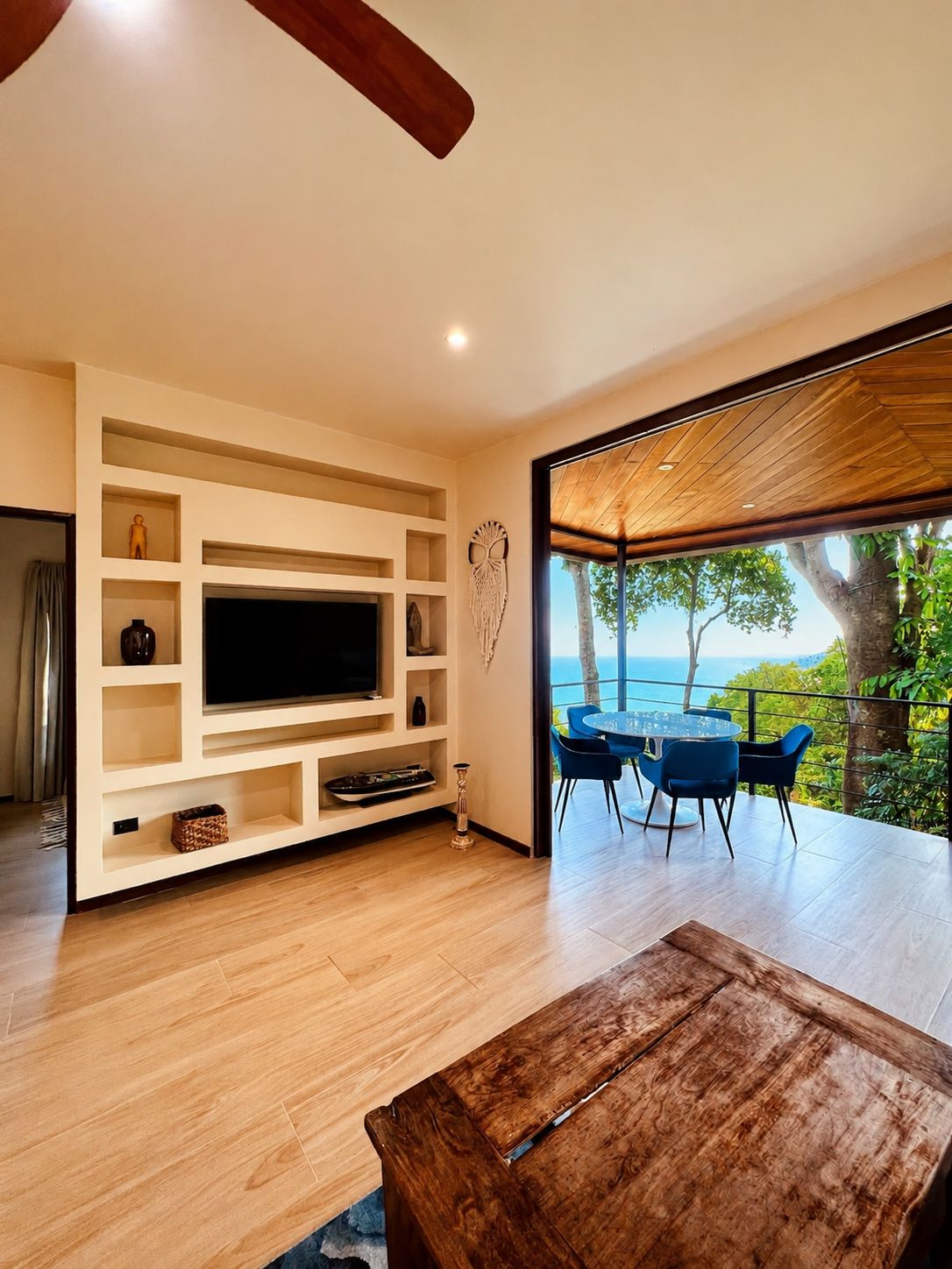 Un salón moderno con televisor empotrado, suelo de madera y vistas al mar.