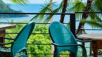 Dos sillas color turquesa con vista a un paisaje verde exuberante y al océano.