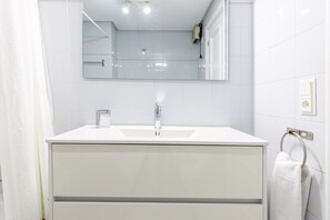 A modern bathroom with a white sink, mirror, and towel ring.