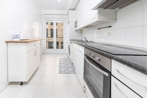Una cocina moderna con armarios blancos, horno empotrado y una encimera con cafetera.