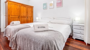 Een hotelkamer met twee bedden, een houten garderobe, witte muren en kunstwerken.