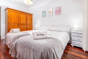 Een hotelkamer met twee bedden, een houten garderobe, witte muren en kunstwerken.