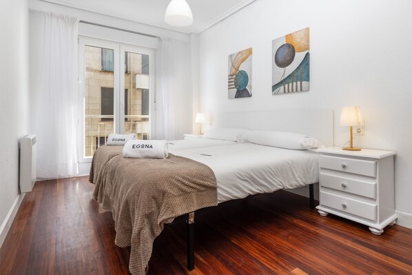 Una habitación de hotel con una cama, una mesita de noche, una lámpara y una obra de arte en la pared.