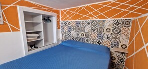 Ein Schlafzimmer mit Bett, Kleiderschrank und Wandfliesen mit Muster.