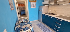 Una cocina compacta con estufa a gas, refrigerador y armarios azules.
