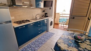 A compact kitchen with a refrigerator, stove, sink, and washing machine. - Apartment 'Balcone Sul Golfo' with Sea View, Wi-Fi and Air Conditioning (Alcamo)