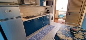 Una cocina compacta equipada con refrigerador, estufa, pileta y lavadora.