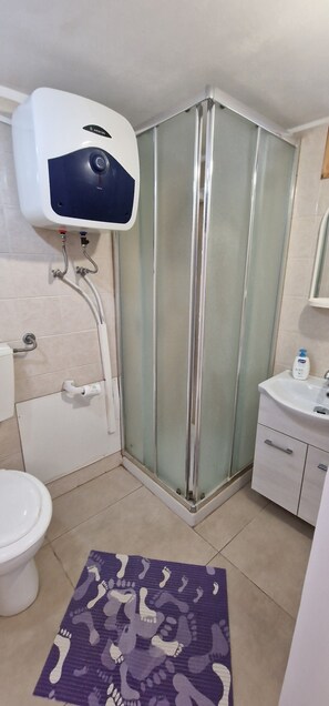 Ein Badezimmer mit Duschkabine aus Glas, einem weißen Waschbecken und einer Toilette.
