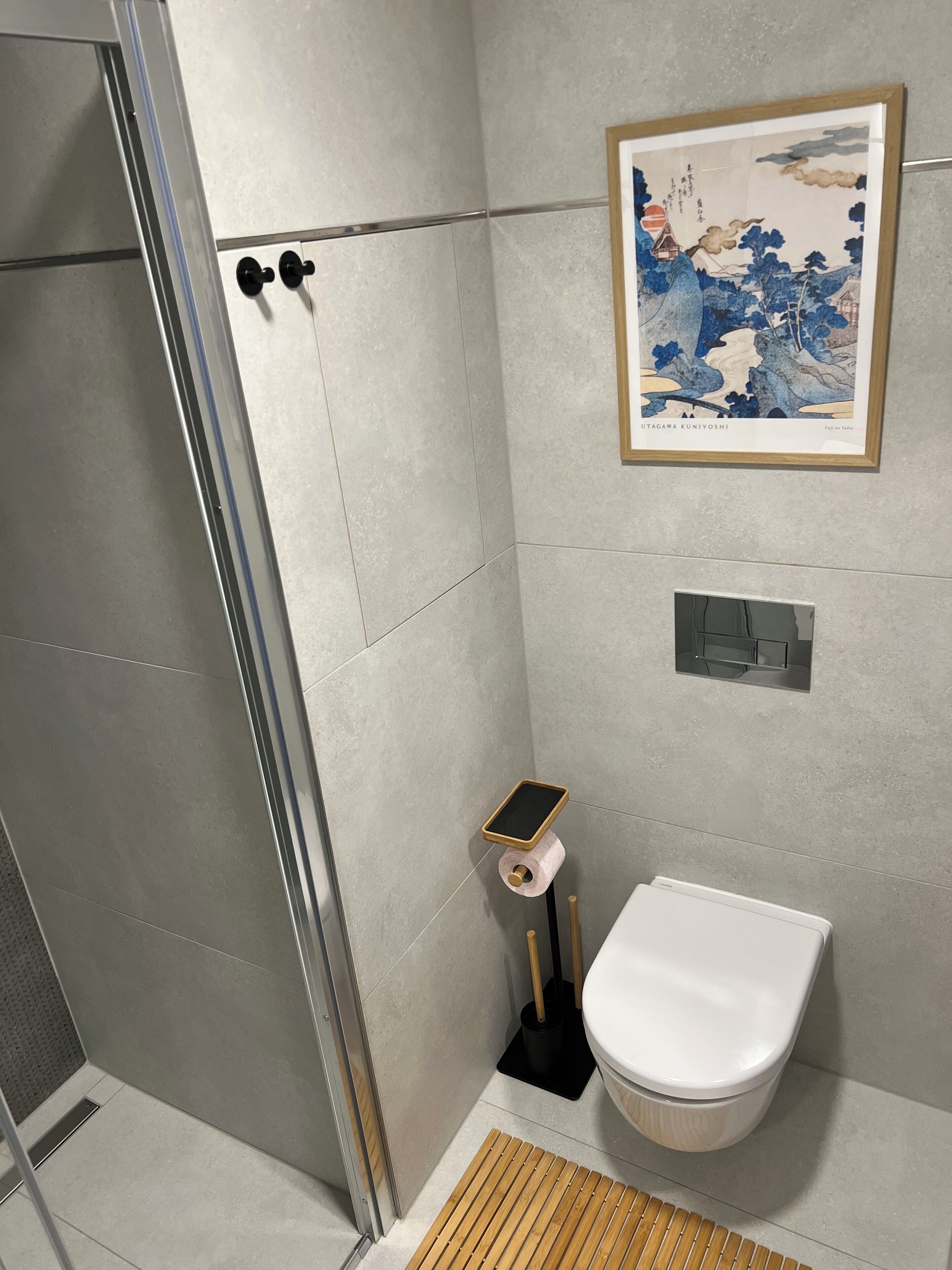 A modern bathroom with a toilet, bidet, and a framed artwork on the wall.