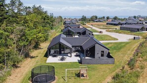 Un complexe résidentiel moderne composé de plusieurs maisons, caractérisé par des toits sombres et de grandes fenêtres.