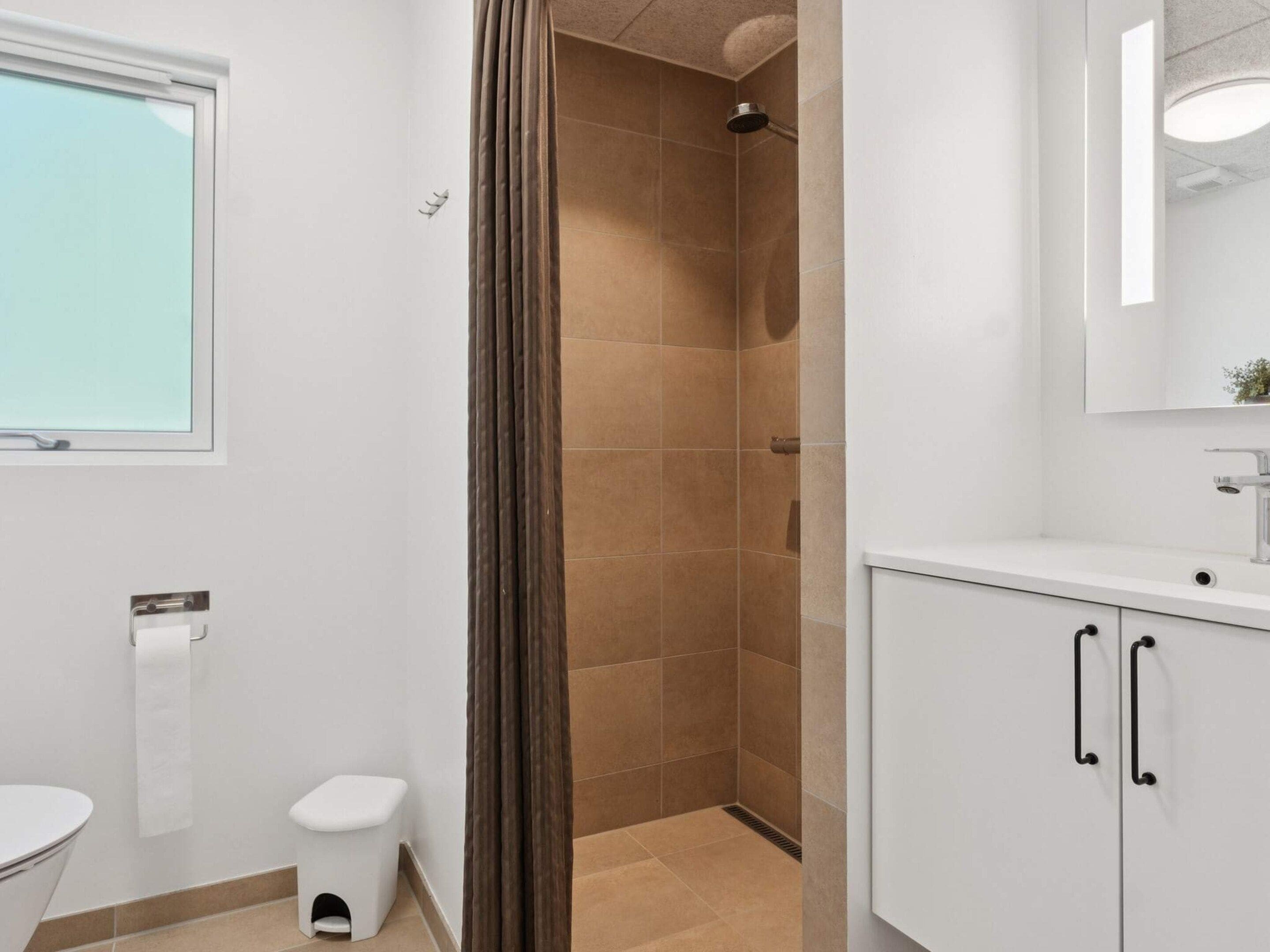 A bathroom with a shower, toilet, sink, and mirror.