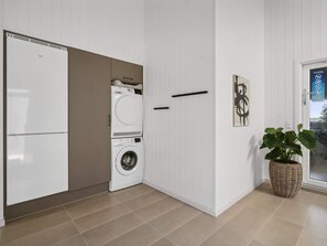 A laundry room with a washing machine and dryer, a door with a handle, and a potted plant. - 5 Star Holiday Home in Otterup (Otterup)