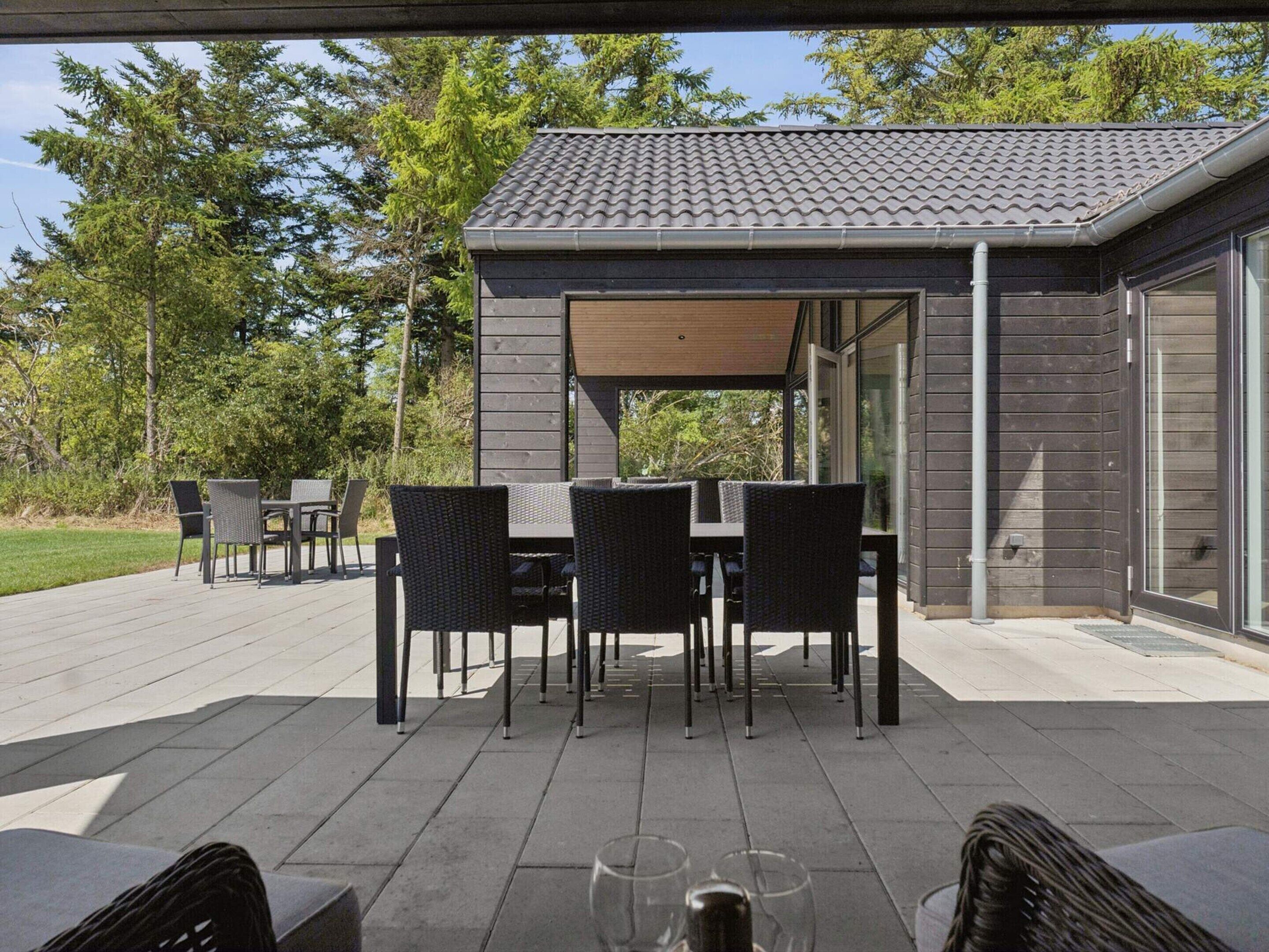 An outdoor patio with a covered dining area, furnished with chairs and tables.