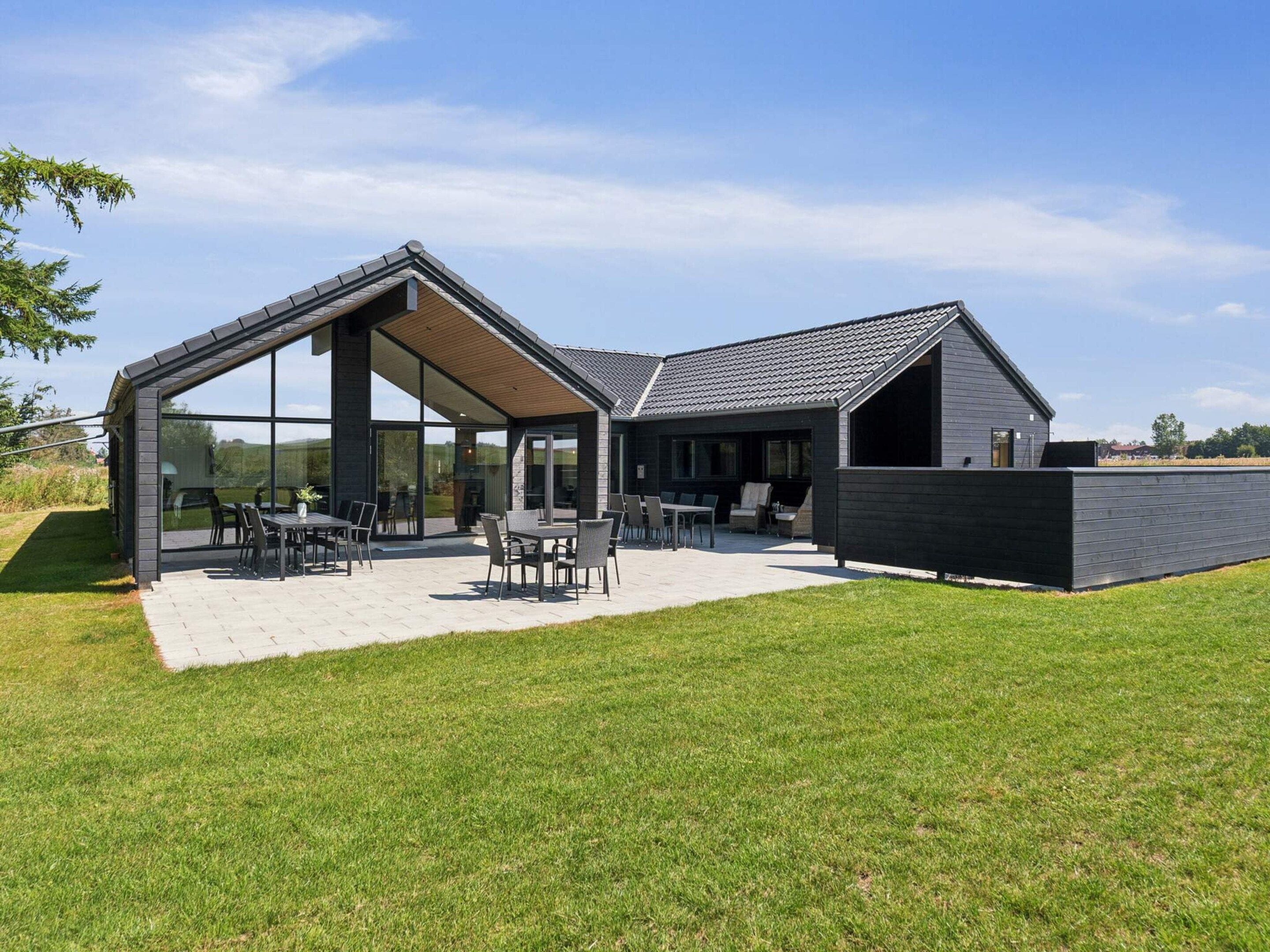 A modern house with a large patio area, a covered outdoor seating area, and a spacious interior.