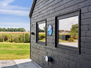 A building with a dark wooden exterior, two windows, and a visible number '23'. - 5 Star Holiday Home in Otterup (Otterup)