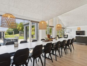 A modern dining area with a long table, black chairs, and three wicker pendant lights. - 5 Star Holiday Home in Otterup (Otterup)