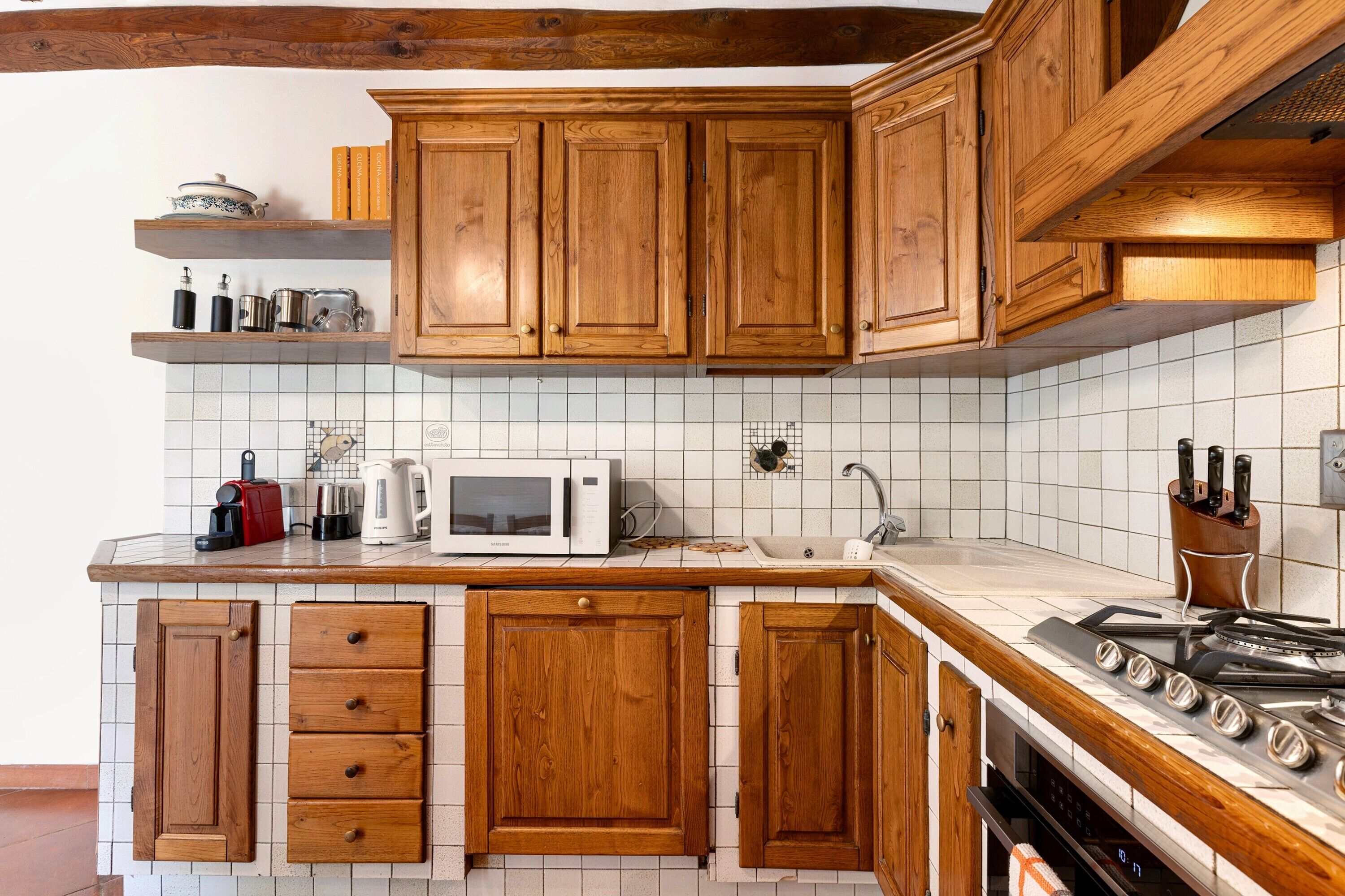 Une cuisine avec des armoires en bois, un four à micro-ondes, une cuisinière et un évier.