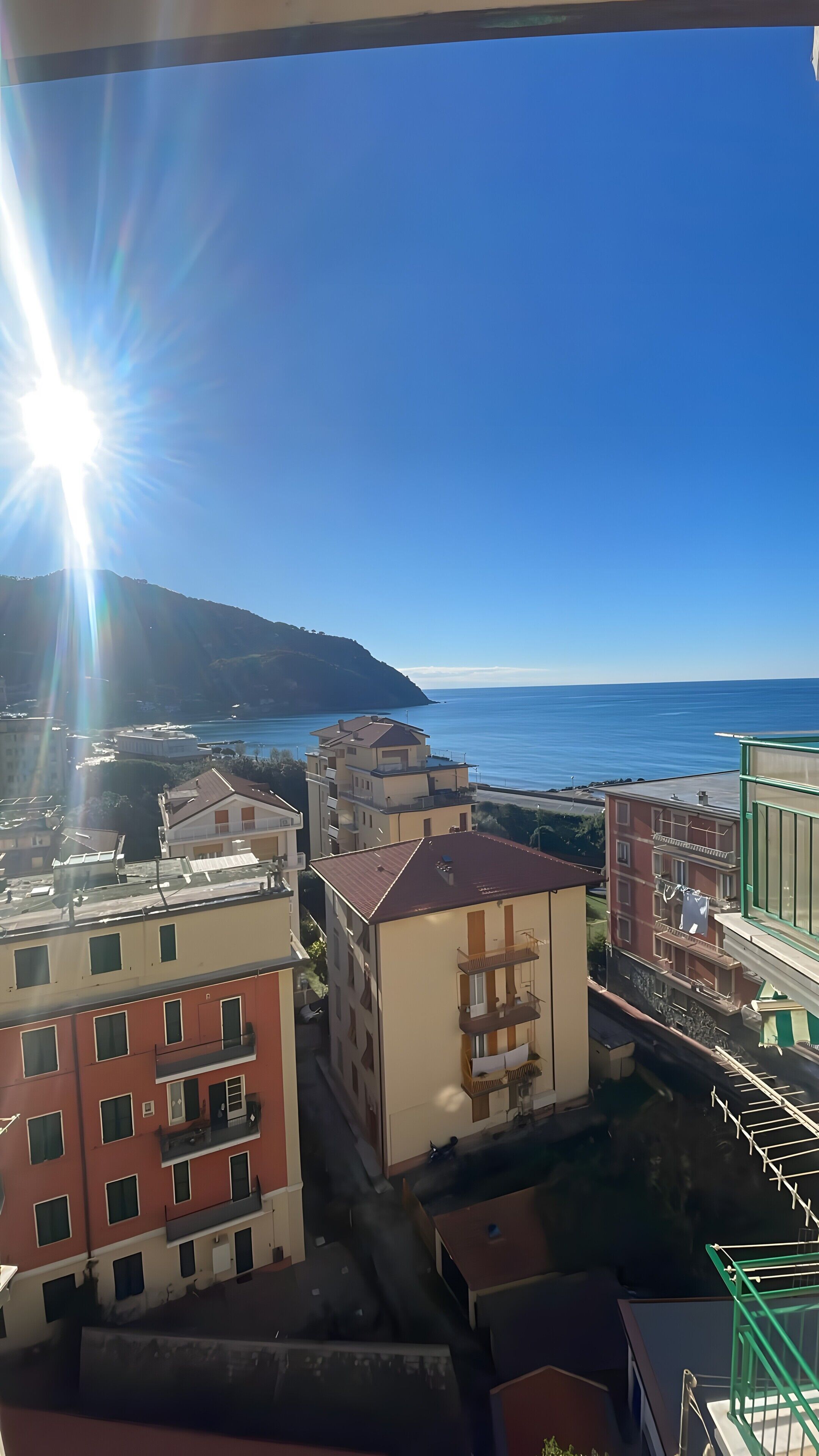 A coastal residential area with buildings, a clear sky, and the sun shining.