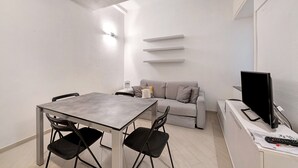 Un espacio habitable compacto con una mesa de comedor, sillas, un sofá, un televisor y un control remoto.