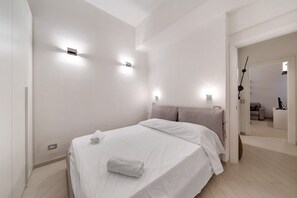 Une chambre d’hôtel moderne avec un lit bien fait, une tête de lit et des lampes fixées au mur.