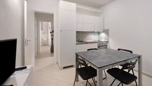 Una cocina moderna con armarios blancos, una mesa de comedor gris y sillas negras.