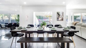 A modern dining area with a long table set for six, surrounded by black chairs. - Heated Pool + Outdoor Theater | Sleeps 16 w/ Games (San Antonio)