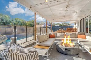 A modern outdoor living area with a fire pit, seating, and a pool.