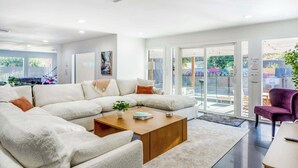 A modern living room with a sectional sofa, a coffee table, and a purple armchair. - Heated Pool + Outdoor Theater | Sleeps 16 w/ Games (San Antonio)