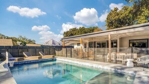 A modern outdoor pool area with lounge chairs and a covered seating area. - Heated Pool + Outdoor Theater | Sleeps 16 w/ Games (San Antonio)