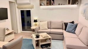 A modern living room with a sofa, a coffee table, a TV, and a bookshelf. - Holiday Home 'Domaine 3016' with Shared Pool, Wi-Fi and Air Conditioning (Roquebrune-sur-Argens)