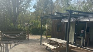 A wooden deck with picnic tables and a hammock. - Holiday Home 'Domaine 3016' with Shared Pool, Wi-Fi and Air Conditioning (Roquebrune-sur-Argens)