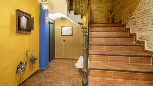 A staircase with wooden steps and a brick wall, a blue wall with a mirror and wall art, and a light fixture.