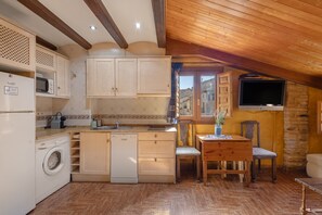 Eine kompakte Küche mit Holzausstattung, einer Waschmaschine, einem Spülbecken und einem Essbereich mit Tisch und Stühlen.