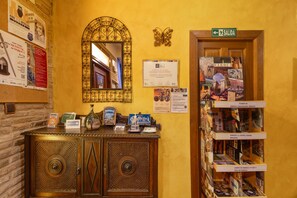 Una zona de recepción con un mueble de madera, un espejo, adornos en la pared y carteles informativos.