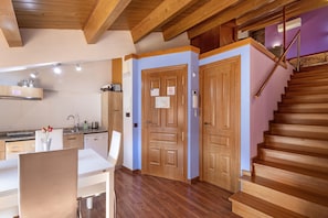 Una cocina moderna con armarios de madera, una mesa de comedor y una escalera que sube a un nivel superior.