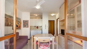 Ein Essbereich mit Tisch und Stühlen, einer Couch, einem Deckenventilator und einer Küche im Hintergrund.