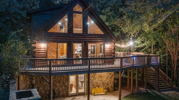 Une cabane en rondins à deux étages, dotée d’un balcon et d’une fondation en pierre.