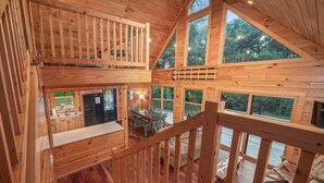 Une cabane en bois à plusieurs niveaux, comprenant un coin repas, une cuisine et un escalier reliant les différents étages.