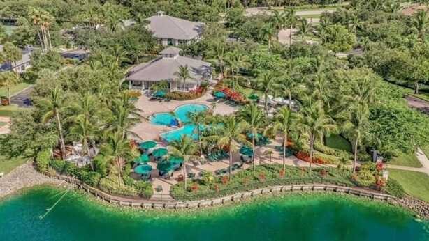 Luchtbeeld van een resort met meerdere zwembaden, palmbomen en een groot wateroppervlak.