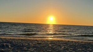 Een strand met de ondergaande zon boven de oceaan.