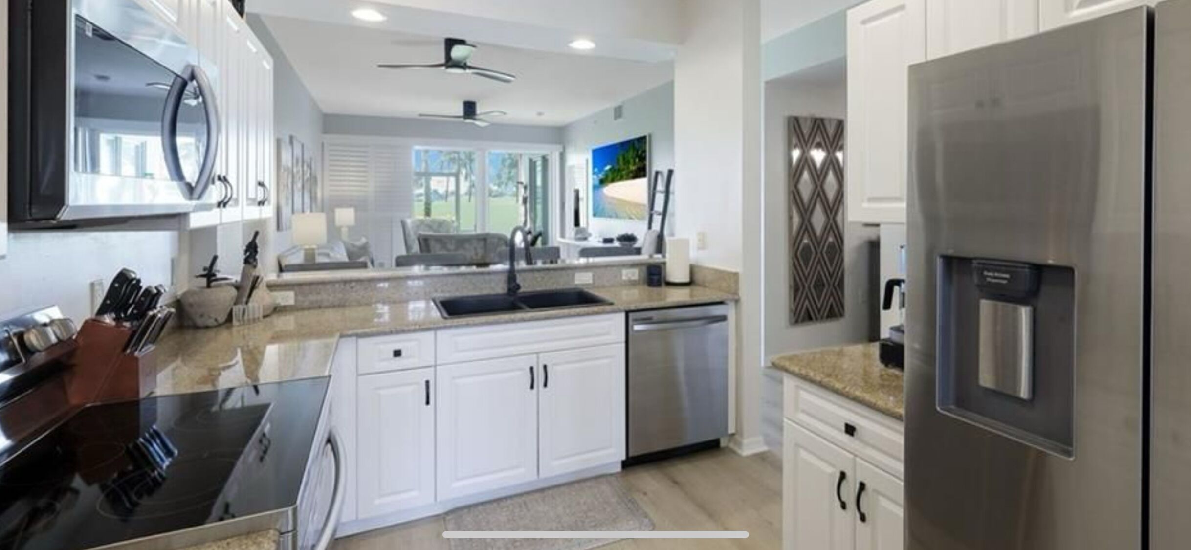 A modern kitchen with white cabinets, stainless steel appliances, and a granite countertop.