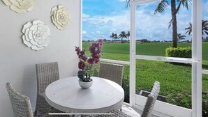 Een ronde tafel met rieten stoelen, een potplant en een wanddecoratie.