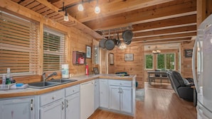 Une cuisine avec des meubles de rangement en bois, un évier et un coin repas comprenant une table et des chaises.