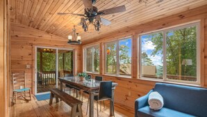 L’intérieur d’un chalet en bois comprend un coin repas, un canapé et de grandes fenêtres qui offrent une vue sur l’extérieur.
